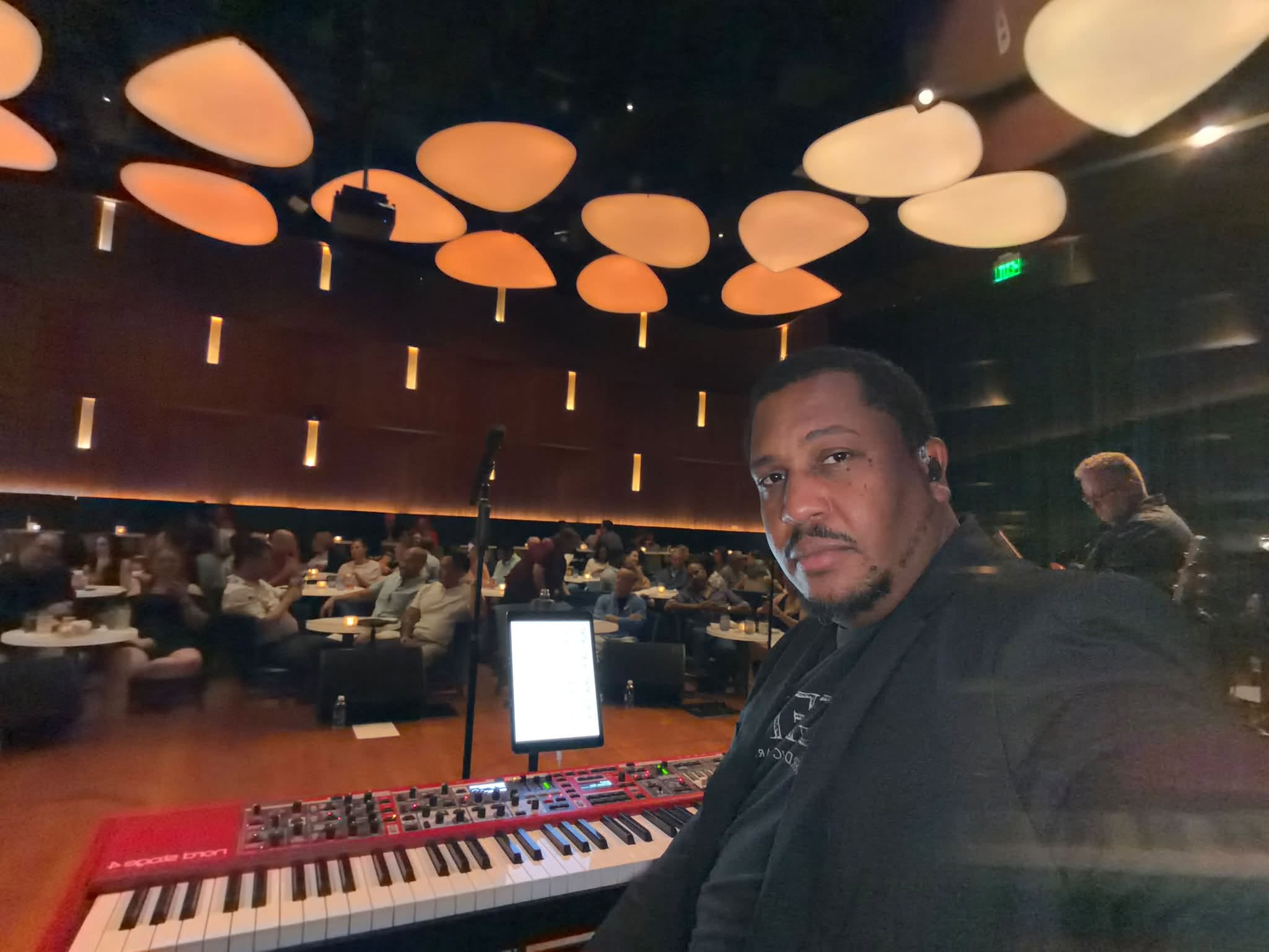Vince at his keyboard setup with a seated audience in the venue